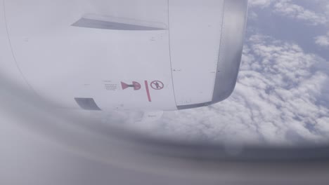 passenger plane engine view from window, flying above clouds in daylight sky