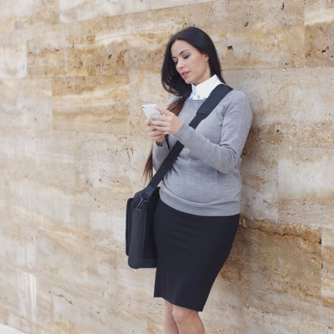 serious woman checking email on phone outdoors