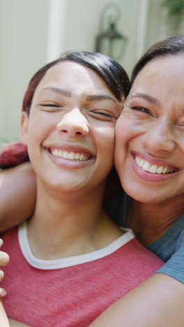 vertical video of portrait of biracial sisters embracing and smiling, in slow motion
