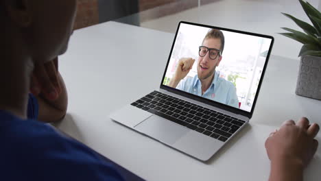 mujer afroamericana hablando en videollamada con un colega masculino en una computadora portátil en la oficina