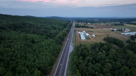 Eine-Luftaufnahme-Des-Verkehrs-Auf-Einer-Autobahn-Im-Späten-Abendlicht-Mit-Der-Letzten-Farbe-Des-Sonnenuntergangs,-Der-Den-Himmel-Verlässt