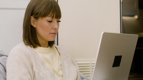 Mujer-Concentrada-Sentada-En-Una-Silla-Y-Trabajando-En-Una-Computadora-Portátil-En-El-Campamento-En-El-Bosque