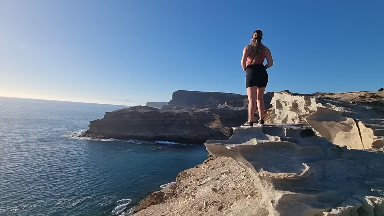 mujer joven observa las maravillosas vistas ubicadas cerca de la playa del medio almud en la isla de gran canaria en un día soleado