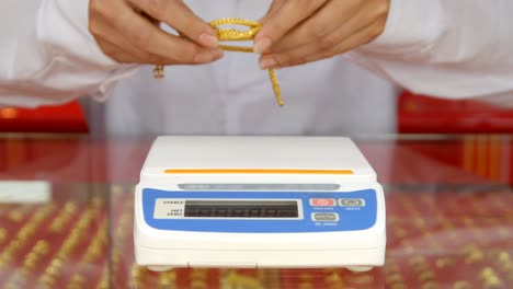 digital scales for weighing gold rings and necklaces with hand in store