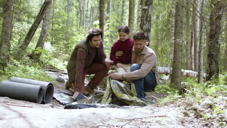 young family setting up tent near the river