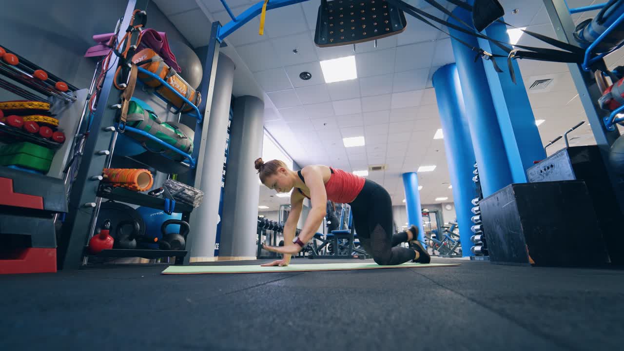 Young girl in sportswear training in the gym. Active woman doing workout on a mat in the modern fitness centre. Healthy lifestyle.