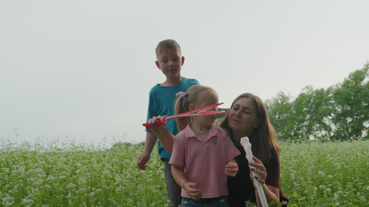백인 엄마와 두 아이가 초원에서 부드럽게 비눗방울 놀이를 하고, 가족이 야생화를 탐험하며 다정하게 껴안는 모습이에요. 나무 사이로 부드러운 햇빛이 쏟아지고, 꾸밈없는 클로즈업 순간과 따뜻한 여름 분위기가 느껴집니다.