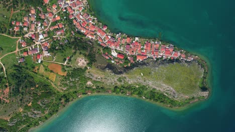 pintoresco pueblo junto al lago de lin con aguas esmeraldas visto desde el aire: la hermosa península rocosa al borde del lago en albania