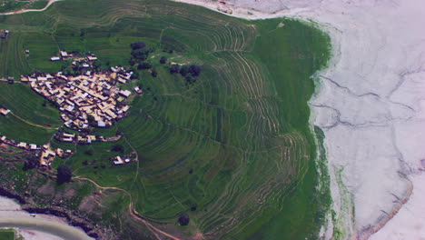 big aerial view over the village surrounded by dry river, mountains and green farms and trees