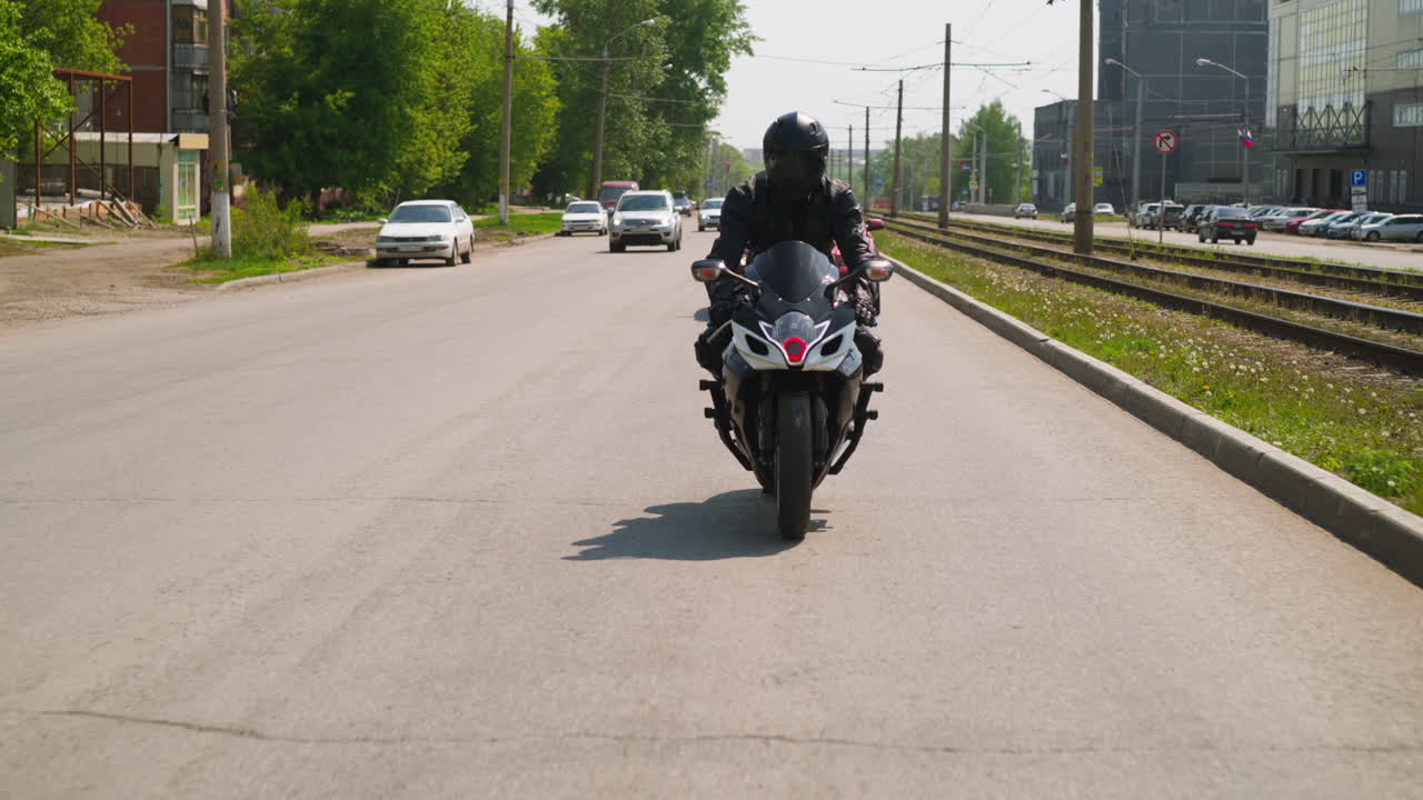 보호 헬 ⁇ 을 입은 남자가 넓은 도로를 따라 오토바이를 운전합니다.