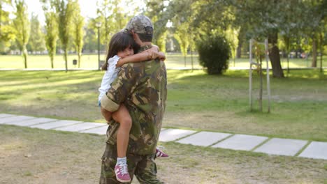 strong military dad holding daughter in arms