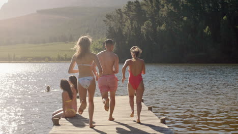 slow motion friends jumping off jetty in lake at sunset having fun splashing in water enjoying freedom sharing summer adventure on vacation