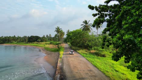 Following-a-car-on-the-coast-surrounded-by-a-magnificent-green-landscape-at-Sao-Tome-e-Principe,Africa