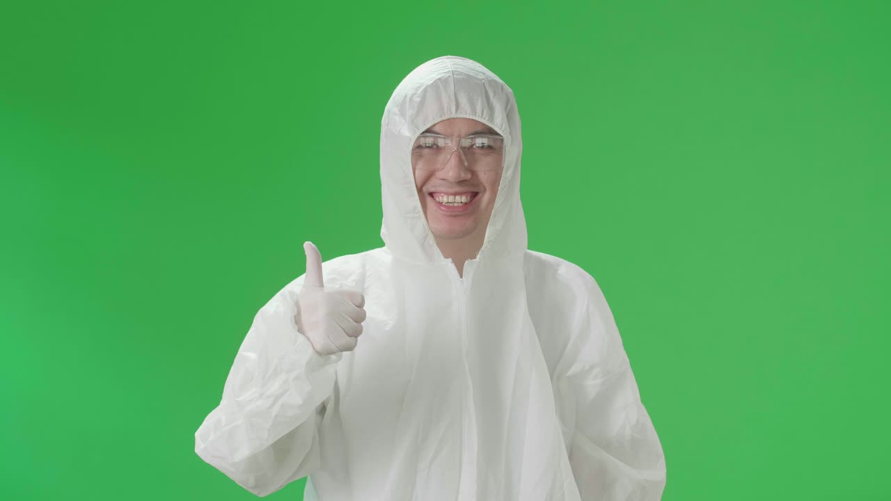 Asian Male Wearing Personal Protective Equipment Uniform Ppe And Showing Thumbs Up In Green Screen Studio