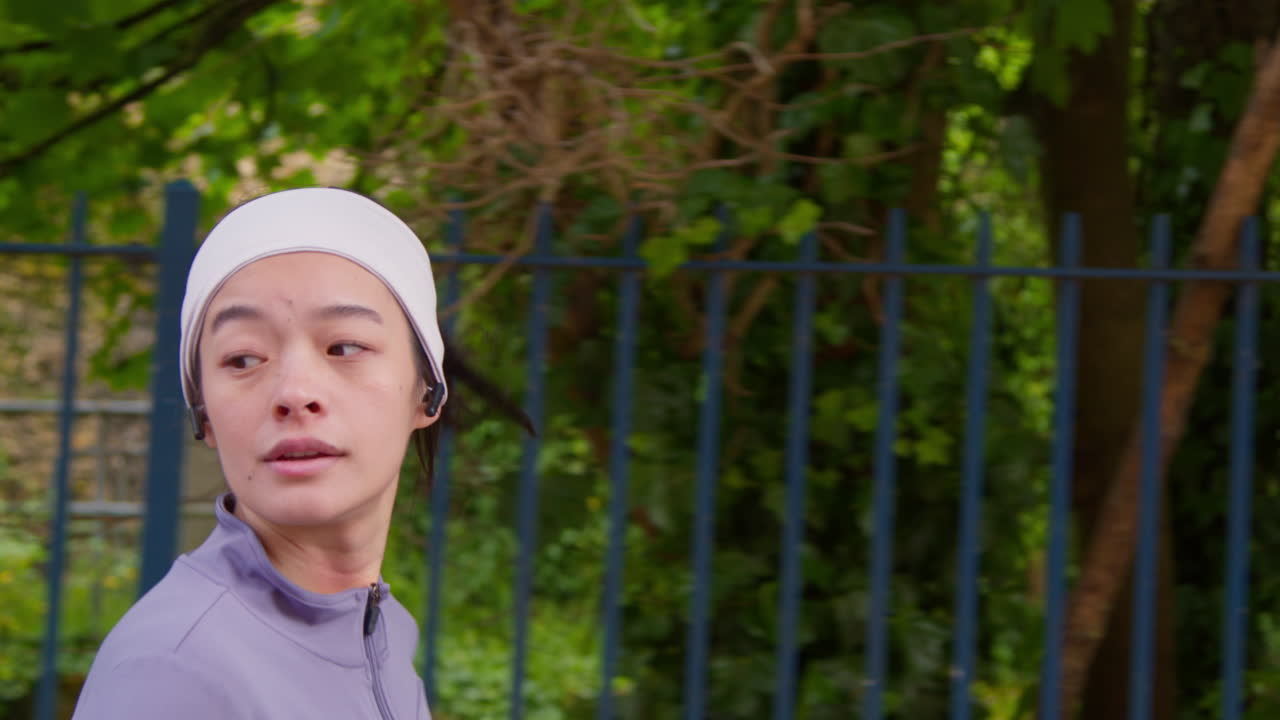 Close Up Side View Of Young Woman Exercising Running Along Urban Street Wearing Wireless Earbuds