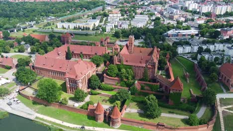 elevated aerial view of malbork castle’s gothic layout, outer walls, and surrounding urban area. malbork, poland