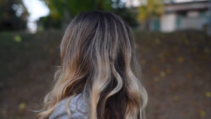 Primer plano de una mujer rubia que se gira y sonríe a la cámara en el parque