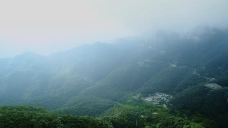 extreme wide shot of yun tai shan geopark's misty green mountains, light rays through mist, and distant winding road in henan province.4k