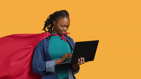 joven vestida de superhéroe para halloween trabajando en una computadora portátil, fondo de estudio