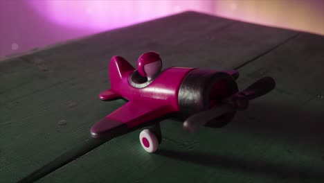 avión de juguete rosa en una mesa de madera