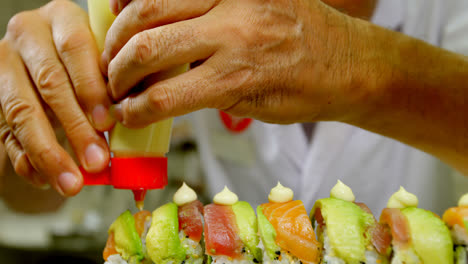 chef masculino cubriendo la salsa en el sushi en la cocina 4k
