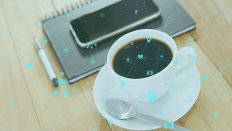 animación de una red de iconos digitales contra un teléfono inteligente, un diario y una taza de café en una mesa de madera.
