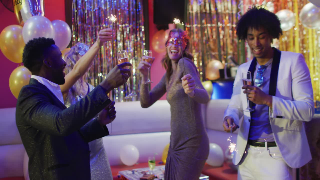 Happy diverse friends dance with sparklers and champagne in a nightclub