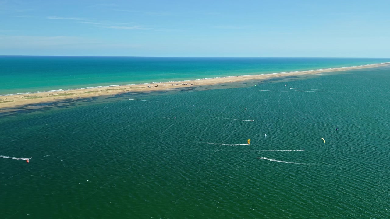 Vue aérienne de kitesurfeurs et de cerfs-volants colorés près du banc de sable de la Punta del Fangar dans le delta de l'Èbre, Espagne. Panorama par drone d'un lagon peu profond, des eaux turquoise de la Méditerranée et d'une destination populaire pour les sports de vent.