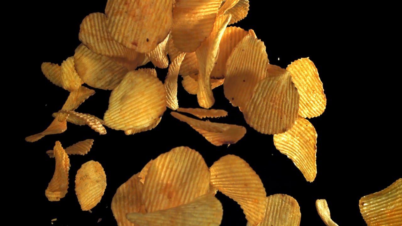 Slow Motion of Crinkle Cut Potato Chips Falling on Black Background