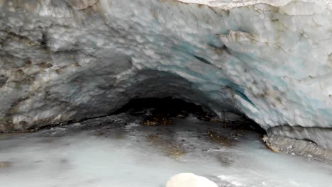 Sobrevuelo-Aéreo-Desde-La-Cueva-De-Hielo-Del-Glaciar-Zinal-En-Valais,-Suiza,-Con-Vistas-A-La-Corriente-De-Agua-Glacial-Que-Se-Derrite,-La-Grieta-Y-El-Valle-Alpino