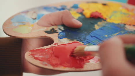 detalle de un pincel mezclando colores en la paleta de un pintor