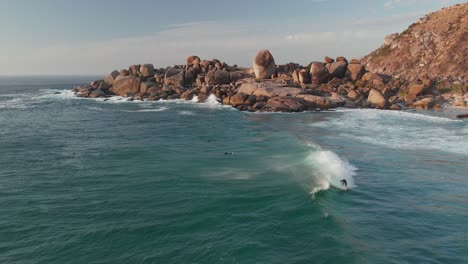 Surfistas-En-Las-Costas-Rocosas-Durante-La-Puesta-De-Sol-En-La-Playa-De-Llandudno-En-Ciudad-Del-Cabo,-Sudáfrica