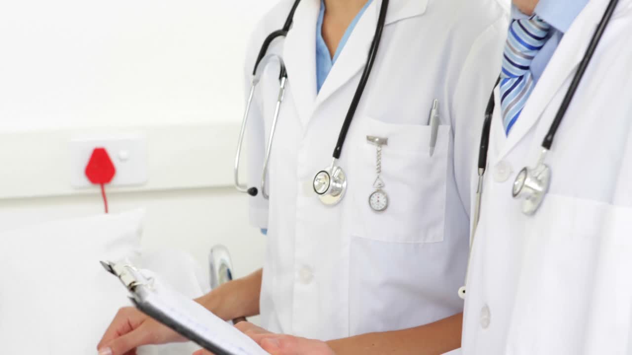 Médicos conversando com paciente doente na cama.