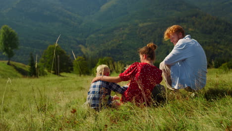 happy family relaxing sitting green hill. parents enjoying holiday with kids.