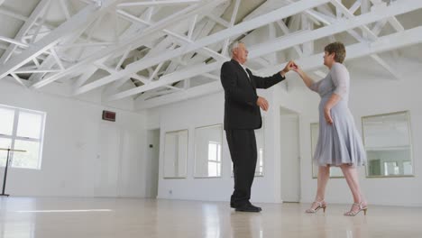 Caucasian-senior-couple-spending-time-together-dancing-in-a-ballroom