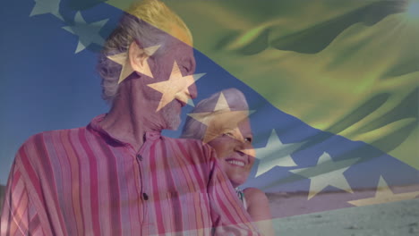 una pareja de ancianos sonrientes en la playa con una animación de bandera ondeando sobre ellos