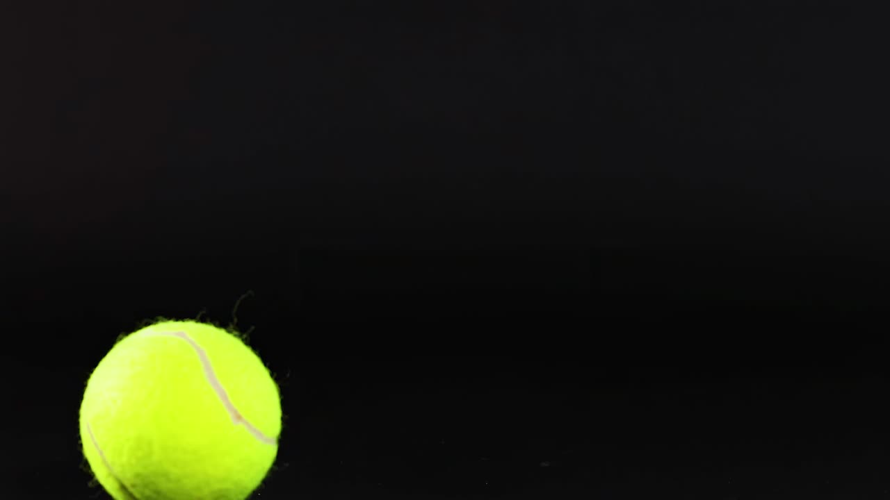 테니스 공이 어두운 배경을 가로질러 굴러