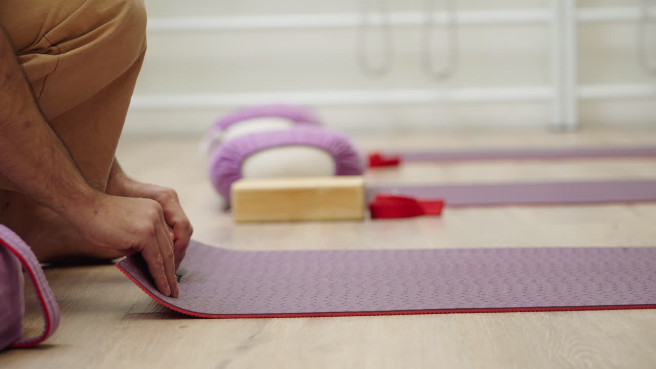 Hombre enrollando la esterilla de yoga después de practicar en un estudio