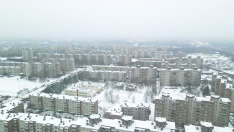 aerial view of apartments houses in winter, snowy environment, flying above apartment houses, soviet chernobyl style attached buildings in kaunas, lithuania, paralax shot