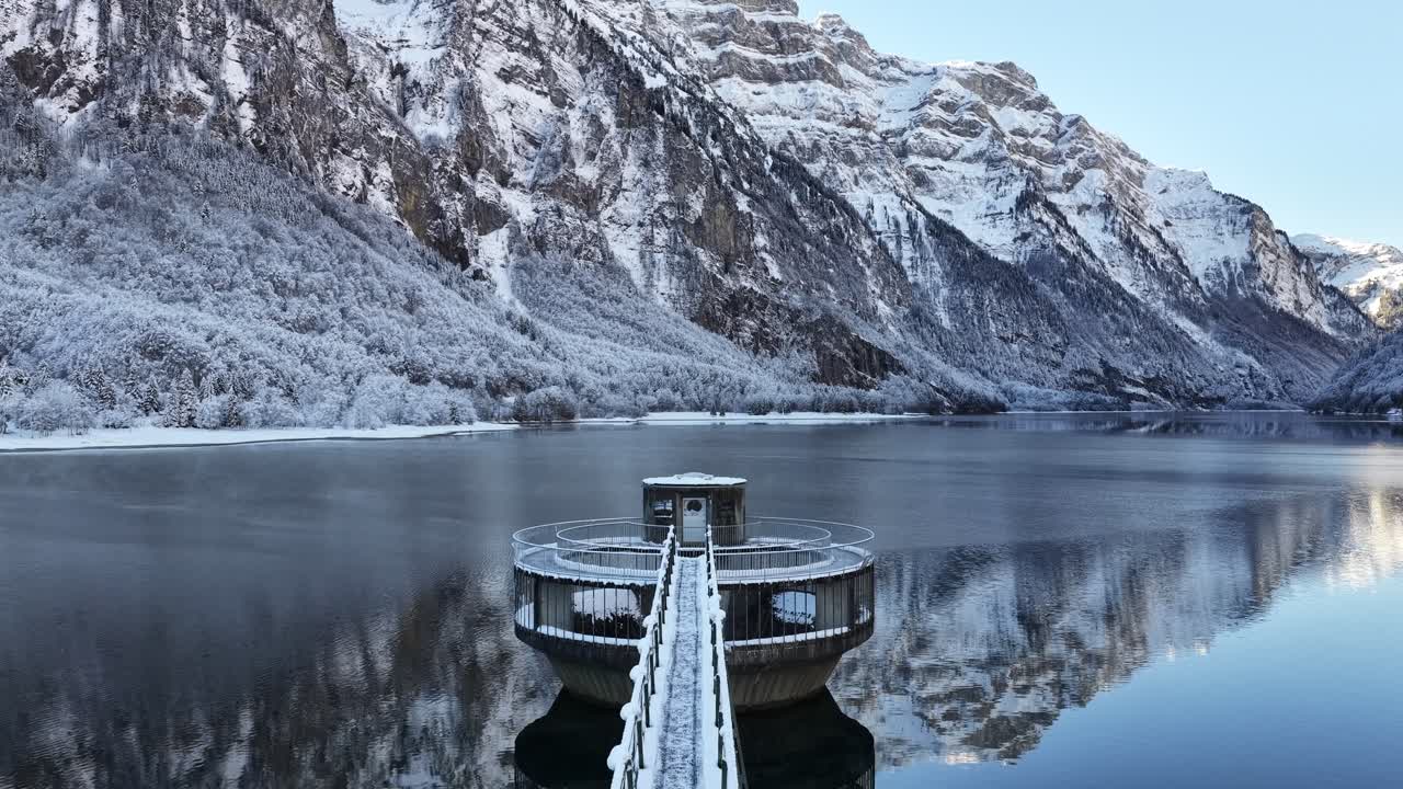 Snow covered platform on Klöntalersee with winter alpine reflections Switzerland