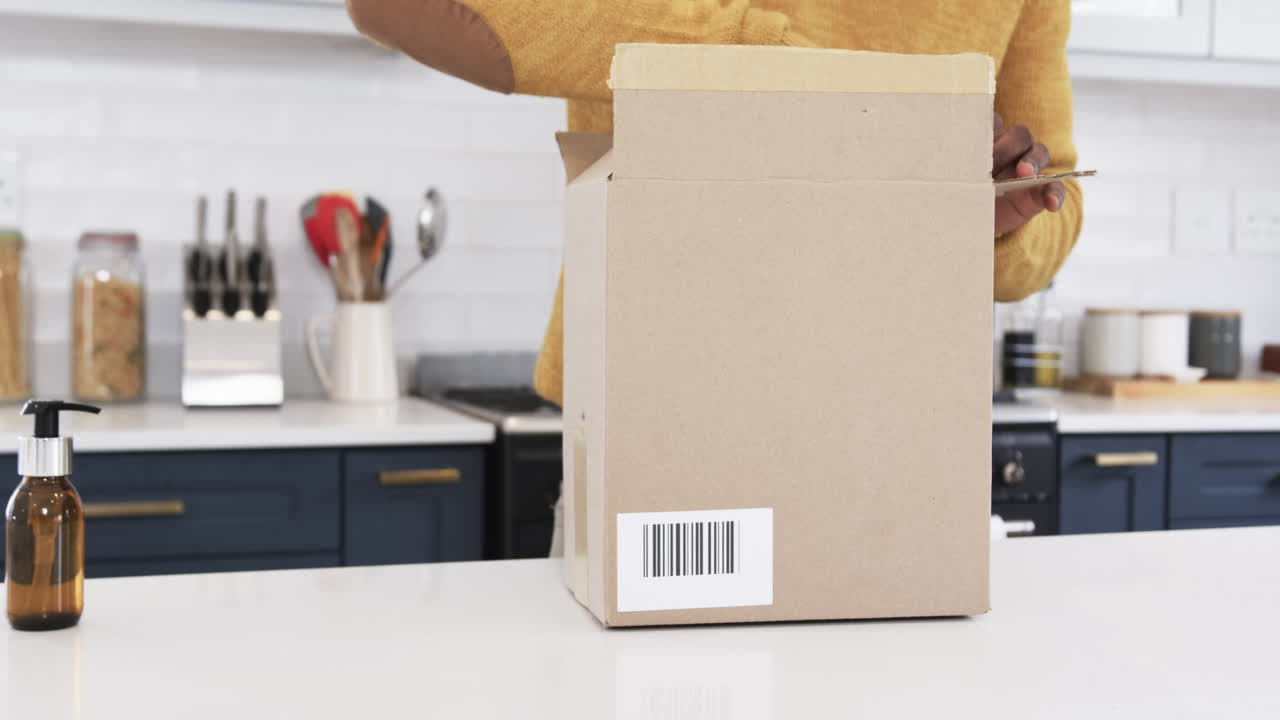 Packing brown bottle into cardboard box in modern kitchen for holiday gift, copy space