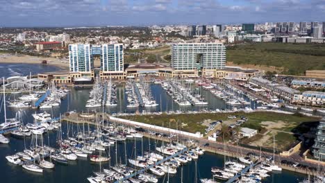 Several-large-sailing-ships-moored-to-the-huge-long-jetties-and-luxury-catamarans-in-the-marina-Herzeliya-in-Israel-with-large-hotels-in-the-background