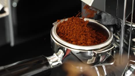 usando una máquina trituradora para moler granos de café frescos para hacer bebidas calientes en la cafetería