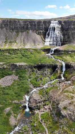 aerial view over the river leading to hrisvaosfoss waterfall in iceland, vertical video.