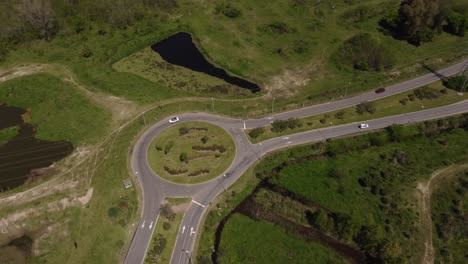 Aerial-view-of-cars-crossing-roundabout-at-interstate-highway,-for-ensuring-road-safety