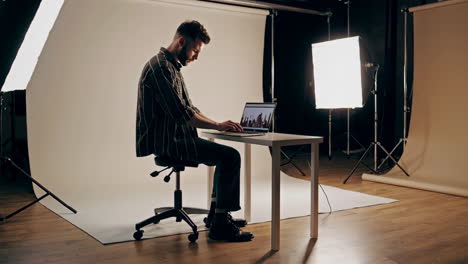 man working on laptop in a photography studio