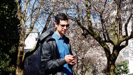 Man-using-mobile-phone-while-having-coffee-in-park-4k