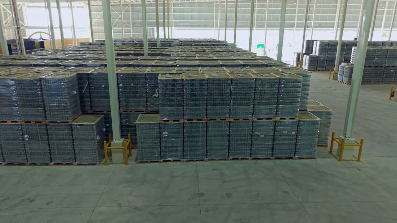 Manufacturing facility warehouse of brewery plant during sunny day in Dominican Republic. Aerial forward flyer pallets with beet bottles