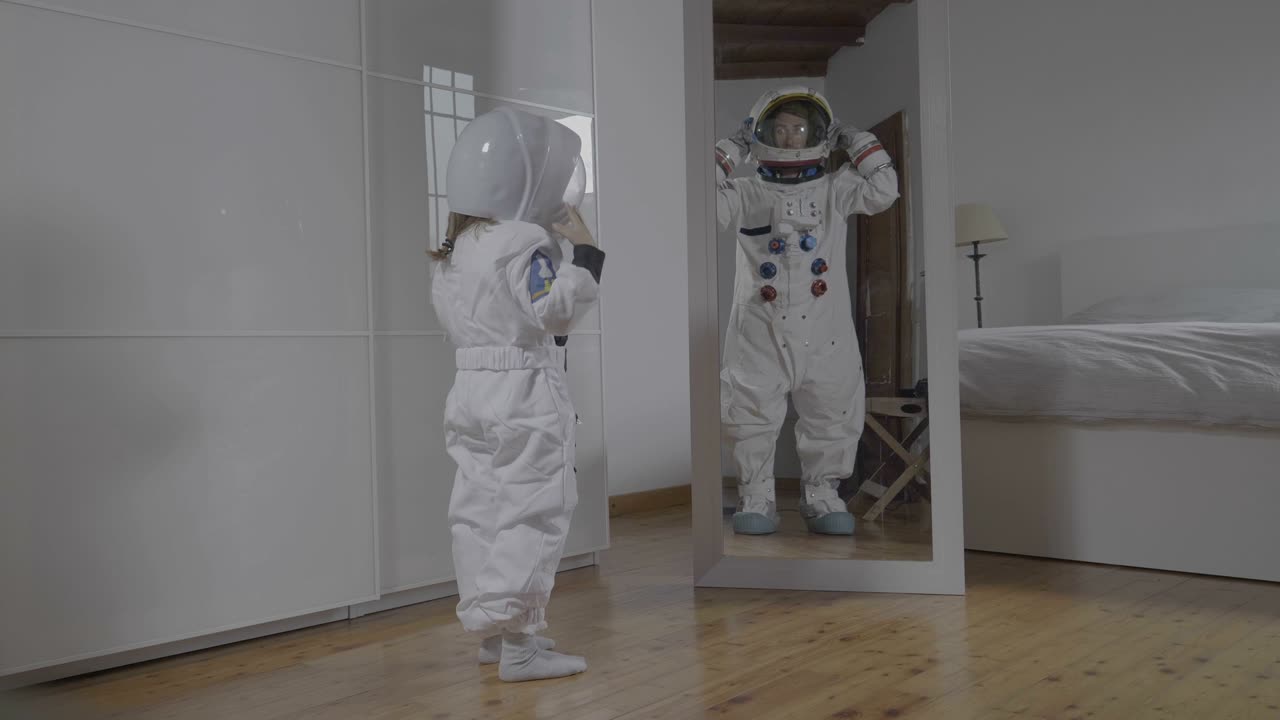 A child looks in front of the mirror wearing the astronaut's suit and looks great, his future, his job, his ambition to grow.