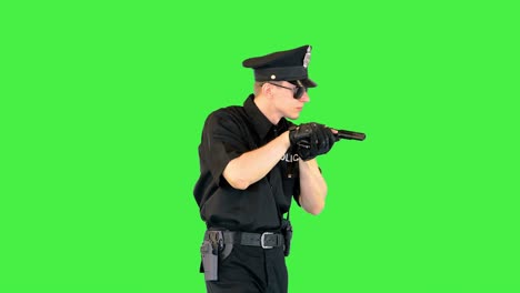 young policeman walks, gets the gun out and takes an aim on a green screen, chroma key